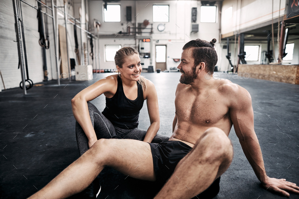 Two fit people relaxing on a gym floor after exercising