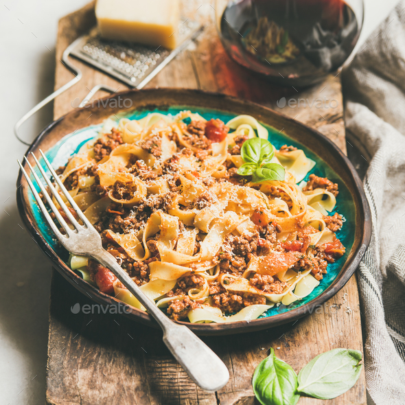 Pasta dinner with tagliatelle bolognese and red wine, square crop
