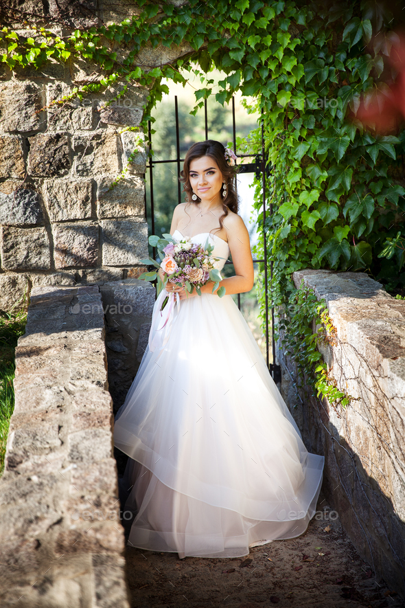 Beautiful young bride with a bouquet of wedding flowers. Holiday dress - Stock Photo - Images