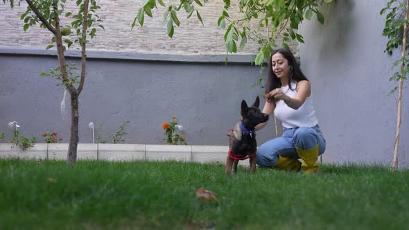 Happy Young Woman Playing with Dog at Garden alt