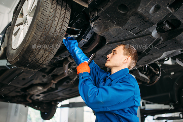 Mechanic with lamp checks car brake hoses - Stock Photo - Images