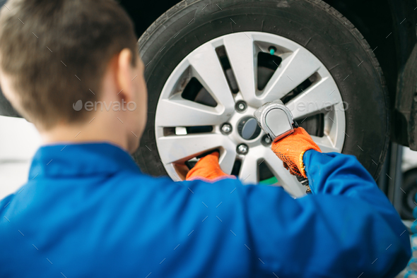 Mechanic unscrews the wheel, tire service - Stock Photo - Images