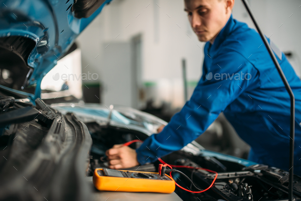Car repairman with multimeter, battery inspection - Stock Photo - Images