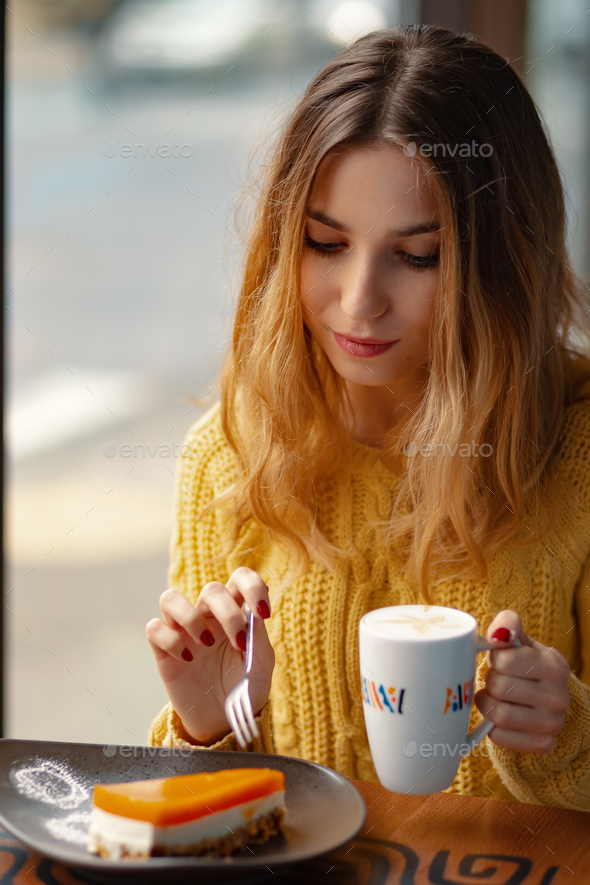 Young woman enjoying a cup of coffee and a slice of delicious ca