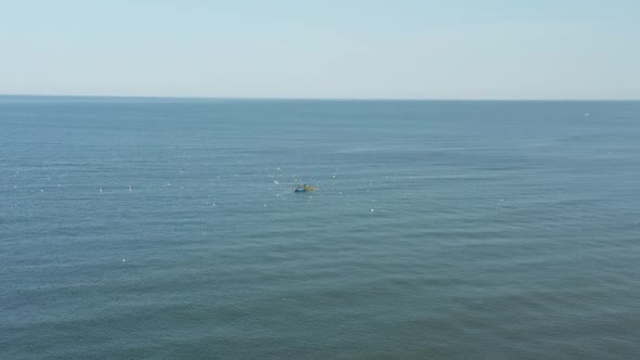 AERIAL: Blue Boat in the Sea on a Sunny Day with Fisherman Catching Fish alt