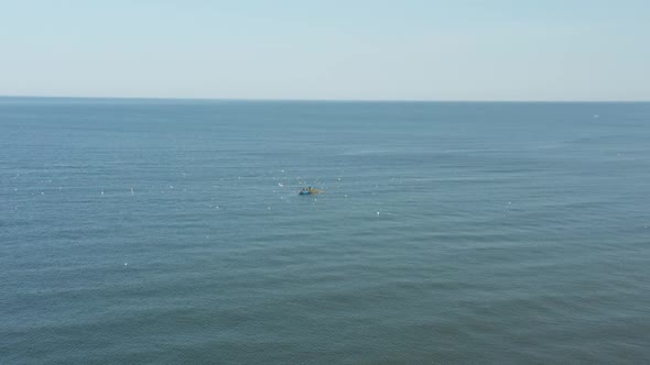 AERIAL: Blue Boat in the Sea on a Sunny Day with Fisherman Catching Fish