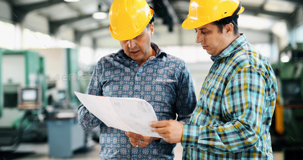 Factory worker discussing data with supervisor in metal factory - Stock Photo - Images