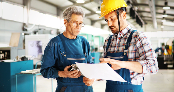Factory worker discussing data with supervisor in metal factory - Stock Photo - Images