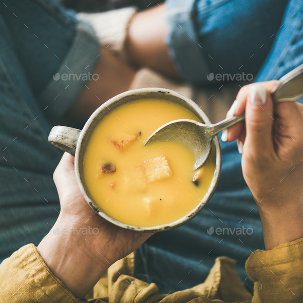 Female keeping mug of warming pumpkin cream soup, square crop - Stock Photo - Images