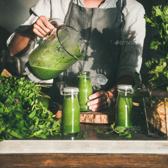 Woman pouring green smoothie from blender to bottle, square crop - Stock Photo - Images