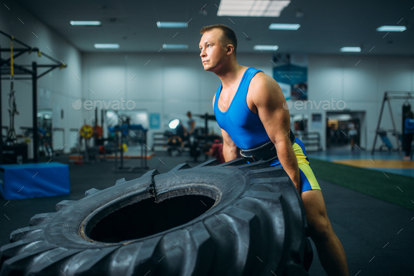Athlete doing exercise with truck tyre, crossfit