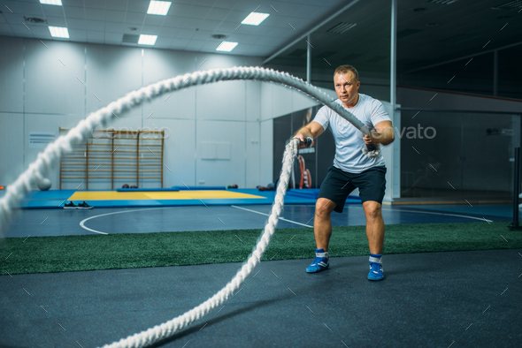 Male athlete with ropes in gym, crossfit workout