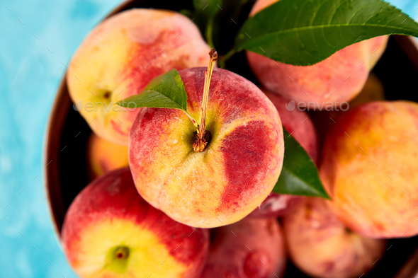 Ripe peaches in a bowl, basket on the blue table - Stock Photo - Images