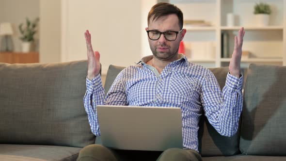 Young Man Reacting To Loss on Laptop at Home  alt