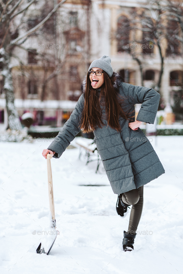 Beautiful girl in winter fashion clothes with a shovel Stock Photo by  simbiothy