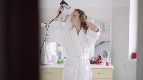 Portrait of Slim Happy Woman Singing Dancing Drying Hair with Hair Dryer in Slow Motion alt