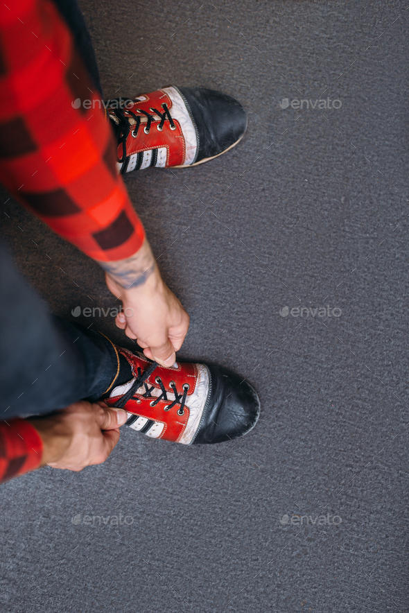 Bowler ties shoelaces on house shoes, top view