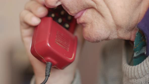 Close up portrait of elderly serious Caucasian man talking on landline wired phone alt