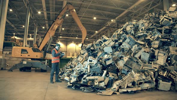 Landfill Worker Is Inspecting a Pile of Rubbish alt