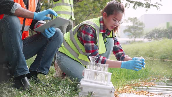 Scientist woman collecting samples of factory wastewater in a test tube alt