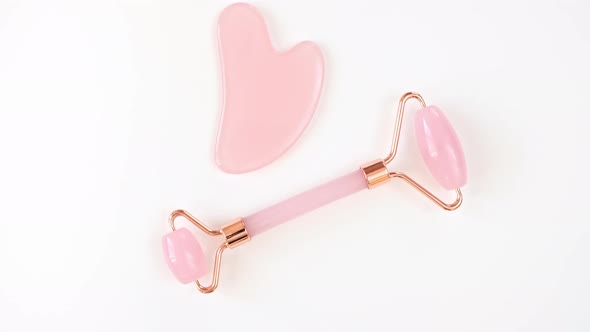Rotation of Pink Quartz Facial Roller and Massage Stone Gua Sha Isolated on White Background Flat alt