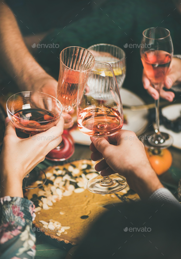 Friends clinking glasses with rose wine at Christmas festive table - Stock Photo - Images