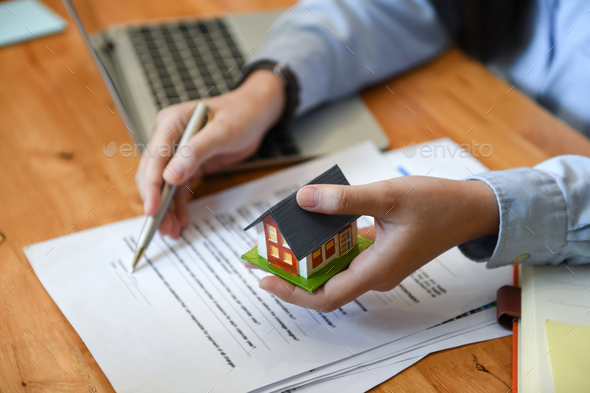 Brokers home sales hold pen and house model in hand. - Stock Photo - Images