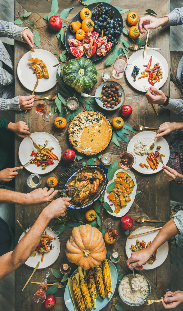 Friends feasting at Thanksgiving Day table with turkey, vertical