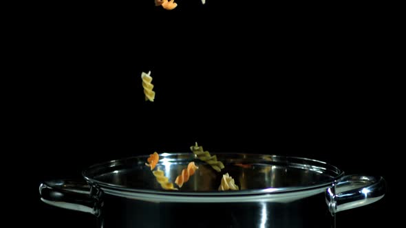Fusilli falling in pot on black background alt