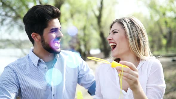 Beautiful Young Couple in Love Blowing Soap Bubbles and Smiling