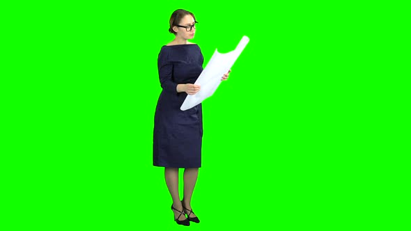 Designer Girl Looks at the Building Drawing. Green Screen alt