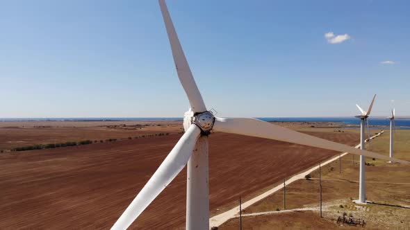 Close Up Aerial View of Wind Turbines Generating Clean Wind Power Among Yellow Fields alt