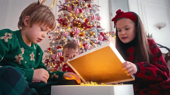 Beautiful Children Boy and Girl Playing Near Christmas Tree Opening Boxes with Presents alt