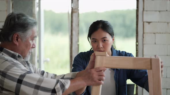 Senior man and young carpenter fit wood together alt