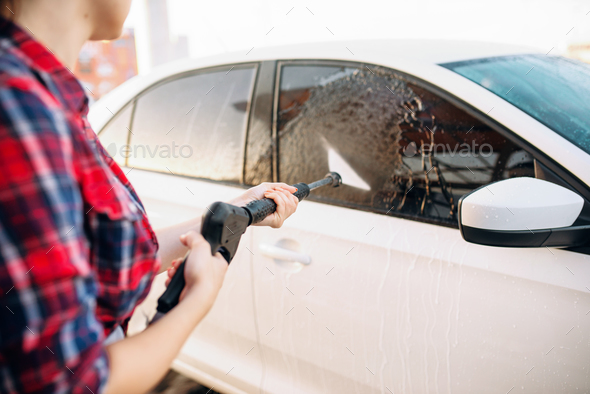 Female person wash off the foam from the car glass - Stock Photo - Images