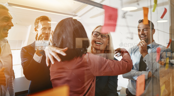 Businesswomen hugging while brainstorming with their team in an office - Stock Photo - Images
