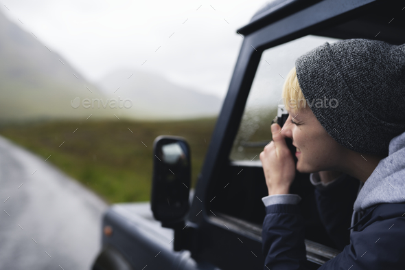 Woman taking a photo out of the car window - Stock Photo - Images