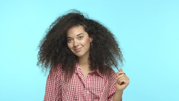 Slow Motion of Beautiful and Silly Woman with Curly Hairstyle Roll a Curl on Finger Looking Away