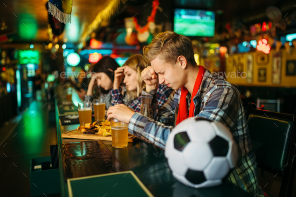 Sad fan covers face with hands in sports bar