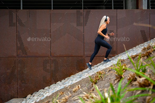 Fit sports women running interval workout in stairs against a metal wall in city - Stock Photo - Images