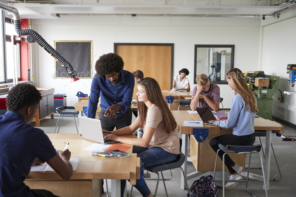 Teacher Talking To Female High School Student Sitting At Work