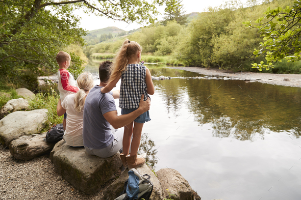 Family On Hike Looking Out Over River In UK Lake District