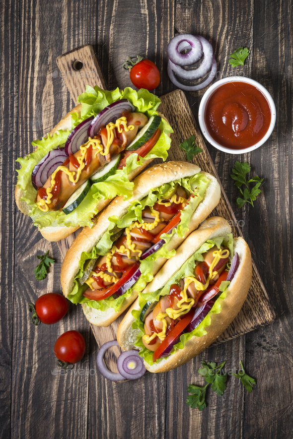 Hot dog with fresh vegetables on dark wooden table Stock Photo by Nadianb