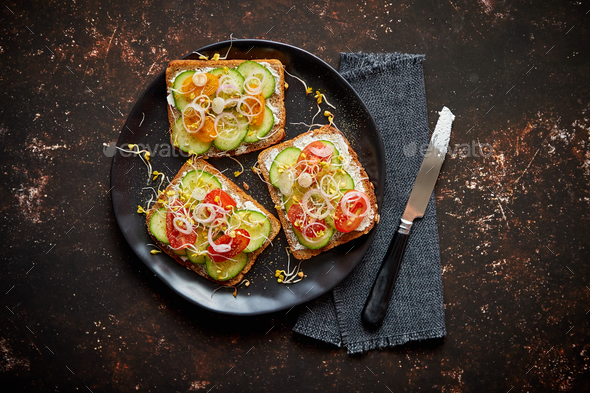 Healthy toasts with cucomber, tomatoes and crumbled feta and radish sprouts
