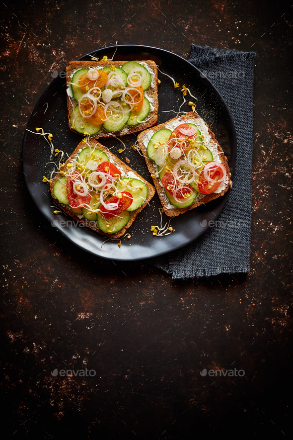 Healthy toasts with cucomber, tomatoes and crumbled feta and radish sprouts