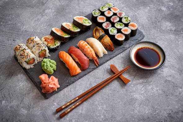 Composition of different kinds of sushi rolls placed on black stone board - Stock Photo - Images