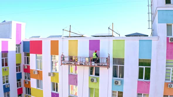 A Worker Paints A Building At A Height