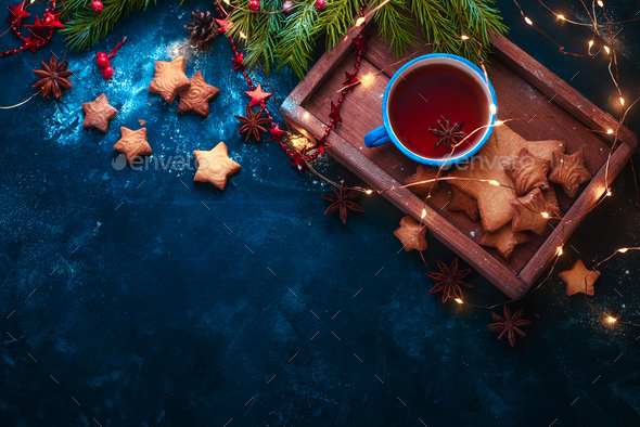 Cookies, tea and fairy lights flat lay with fir tree branches, wooden tray, anise stars, and