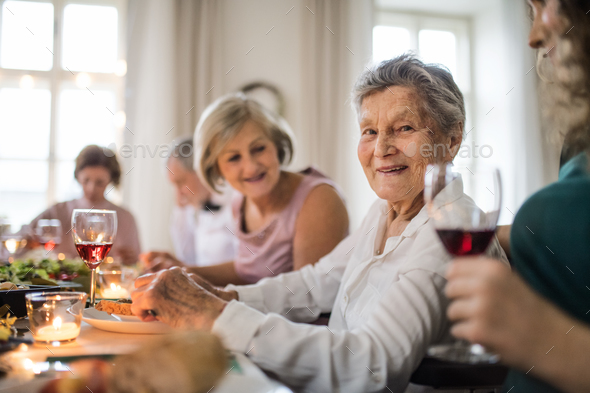 An elderly women with a family sitting at a table on a indoor family birthday party. - Stock Photo - Images