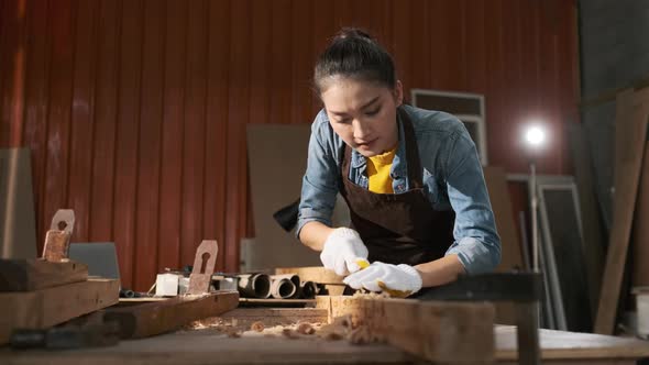 Young Asian female carpenter gouge for wood on carpenter workbench